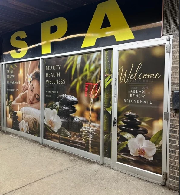 Spa storefront with full-height window graphics showing orchids, stacked stones and wellness imagery.